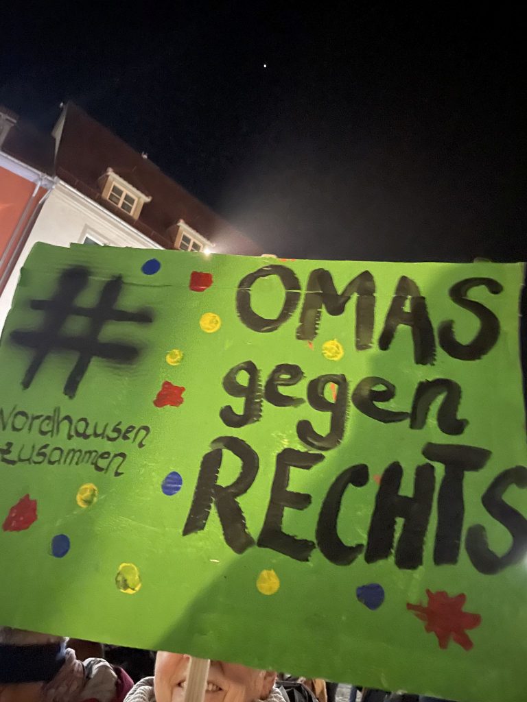 Ein grünes Plakat mit bunten Farbklecksen. Text: #NordhausenZusammen - Omas gegen Rechts